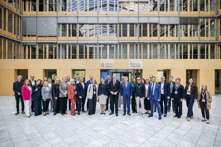 The Latvian delegation in the glass-roofed atrium of the Haus der Deutschen Wirtschaft, under the BDI and BDA signs.