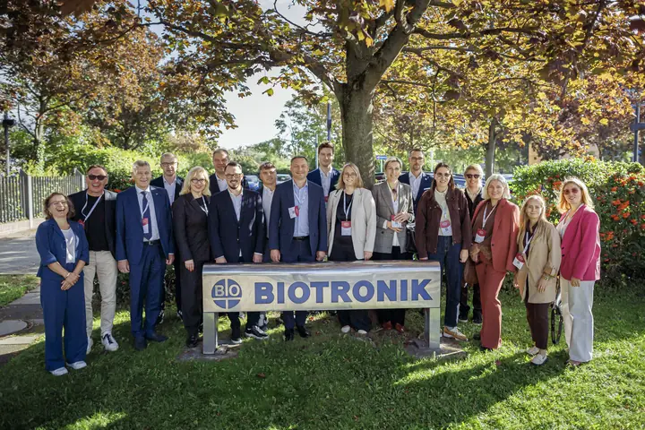The life sciences group standing behind the BIOTRONIK sign under autumn trees.