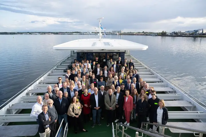 Conference participants gathered on the open deck of a ship on the Warnow, seen from above.