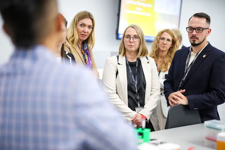 Aleksandrs Gusevs of Double Helix Technologies and other delegation members listening to an Illumina specialist in the laboratory.