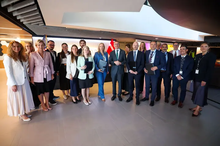 Representatives of the Latvian institutions and of Illumina holding the signed memoranda, with the US and Latvian flags behind them.