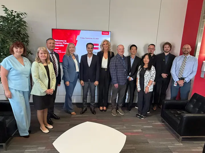 The delegation and its hosts in front of a screen reading Welcome to Thermo Fisher Scientific.