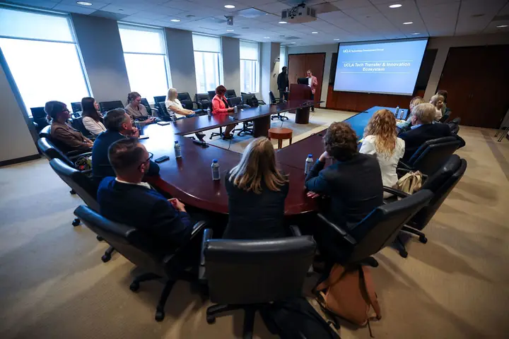 The delegation around a boardroom table during a presentation on the UCLA tech transfer and innovation ecosystem.